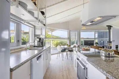 a kitchen with white appliances and a table with chairs at BL1534-Blokhus-Taarnfalkevej-10 in Blokhus