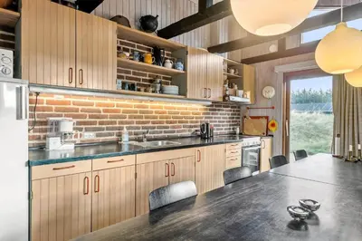 a kitchen with wooden cabinets and a brick wall at BL1697-Pandrup-Marsvinet-34 in Pandrup