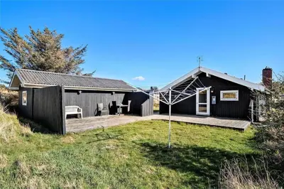 a black house with a deck and a yard at BL244-Blokhus-Moreavej-17 in Blokhus