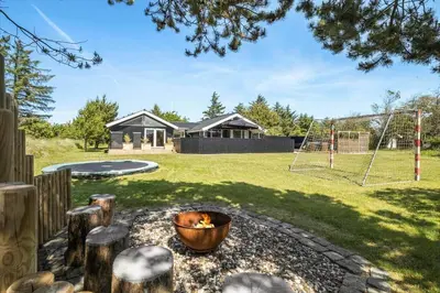 a backyard with a fire pit and a playground at BL1346-Blokhus-Septimusvej-19 in Blokhus
