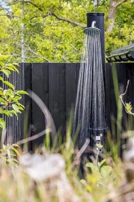 a water shower hanging from a black fence at BL958-Blokhus-Havorns-Alle-14 in Blokhus