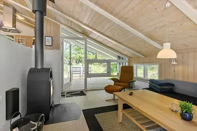 a living room with a fireplace and a table at BL1636-Saltum-Saltum-Strandvej-140 in Saltum