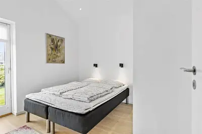a bed sitting in a room next to a door at BL698-Blokhus-Kr-Thomsensvej-3 in Blokhus