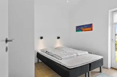 a bed sitting in a room next to a door at BL698-Blokhus-Kr-Thomsensvej-3 in Blokhus