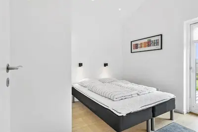 a bed in a white room next to a door at BL698-Blokhus-Kr-Thomsensvej-3 in Blokhus