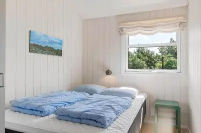 a bed with blue sheets in a room with a window at BL1243-Saltum-Kvansletten-22 in Saltum
