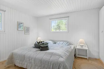 a bedroom with a bed in a white room at BL1668-Blokhus-Skraavejen-4 in Blokhus