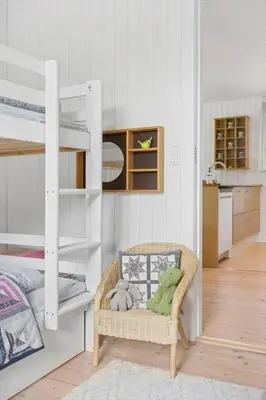 a room with a bunk bed and a wicker chair at BL1668-Blokhus-Skraavejen-4 in Blokhus