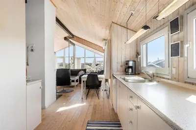 a kitchen with white cabinets and a table with chairs at BL971-Blokhus-Slugten-10 in Blokhus
