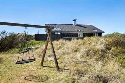 a house sitting on top of a hill with a swing at BL971-Blokhus-Slugten-10 in Blokhus