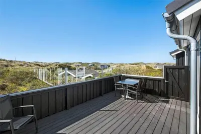 a patio with a table and chairs on a deck at BL971-Blokhus-Slugten-10 in Blokhus