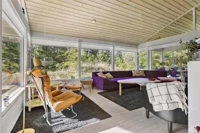 a living room with a purple couch and windows at BL164-Saltum-Lyngsletten-7 in Saltum