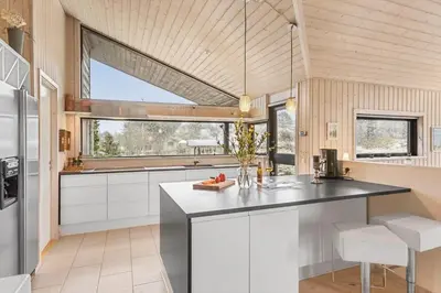 a kitchen with white cabinets and a large window at BL842-Blokhus-Laerkevej-29 in Blokhus