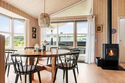 a dining room with a table and chairs and a fireplace at BL1399-Saltum-Laustvej-30 in Saltum