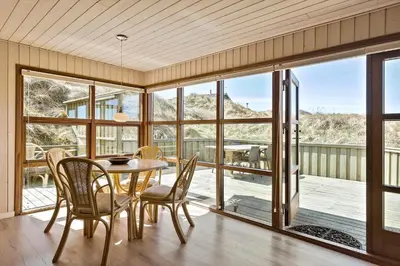 a dining room with a table and chairs and a balcony at BL1311-Saltum-Kordalsvej-90 in Saltum
