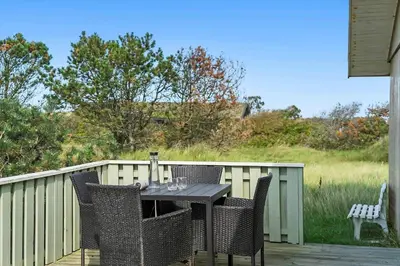 a table and chairs on a deck with a fence at BL1448-Pandrup-Hunetorp-Klitvej-215 in Pandrup