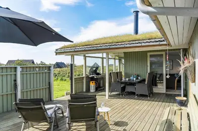 a deck with a table and chairs and an umbrella at BL1448-Pandrup-Hunetorp-Klitvej-215 in Pandrup