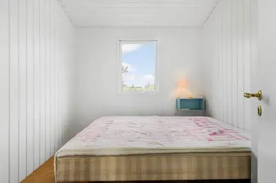 a white room with a bed and a window at BL1471-Blokhus-Solbakkevej-15 in Blokhus