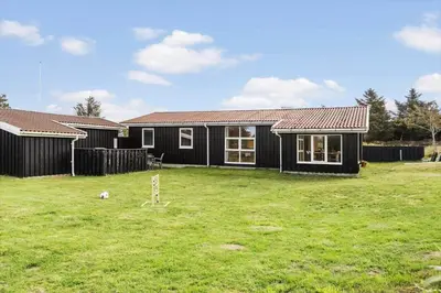 a black house with a lawn in front of it at BL1471-Blokhus-Solbakkevej-15 in Blokhus