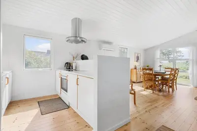 a kitchen with white cabinets and a dining room with a table at BL1471-Blokhus-Solbakkevej-15 in Blokhus
