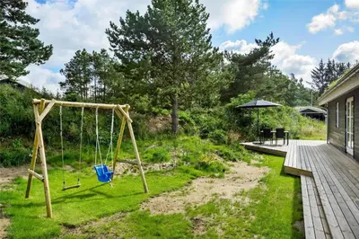 a swing set in a yard next to a house at BL1704-Blokhus-Pirupvejen-66 in Blokhus