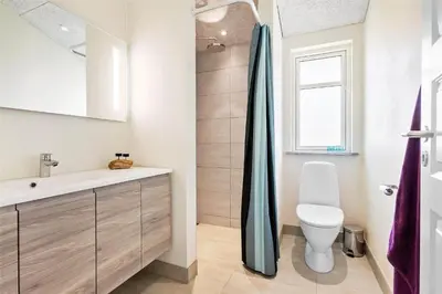 a bathroom with a toilet and a sink and a window at BL1704-Blokhus-Pirupvejen-66 in Blokhus