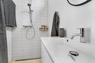 a white bathroom with a sink and a shower at BL1550-Blokhus-Poppelvej-10 in Blokhus