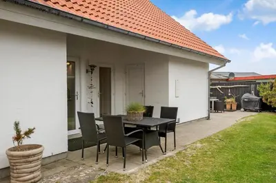 a black dining table and chairs on a patio at BL1567-Blokhus-Klitvejen-6 in Blokhus