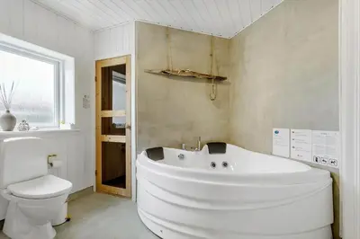 a white bathroom with a tub and a toilet at BL1567-Blokhus-Klitvejen-6 in Blokhus