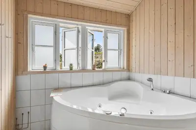 a large white tub in a room with windows at BL1639-Blokhus-Bloksbjerg-57 in Blokhus