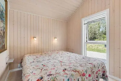 a bedroom with a bed with a floral bedspread and a window at BL1262-Pandrup-Hunetorp-Klitvej-5 in Pandrup