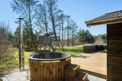 a wooden deck with a hot tub and a playground at BL1236-Pandrup-Kirkekrogen-5 in Pandrup