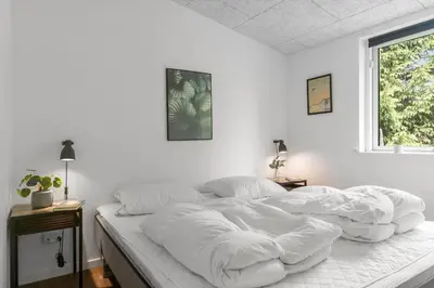 a white bedroom with a large bed with white sheets at BL191-Blokhus-Bloksbjerg-13 in Blokhus