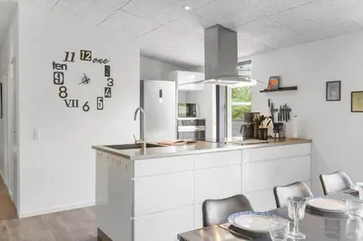 a kitchen with a table and a clock on the wall at BL191-Blokhus-Bloksbjerg-13 in Blokhus