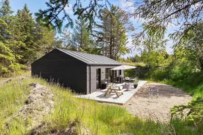 a small black shed with a picnic table and umbrella at BL1565-Blokhus-Plantagevej-2-A in Blokhus