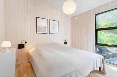 a bedroom with a white bed and a window at BL1565-Blokhus-Plantagevej-2-A in Blokhus
