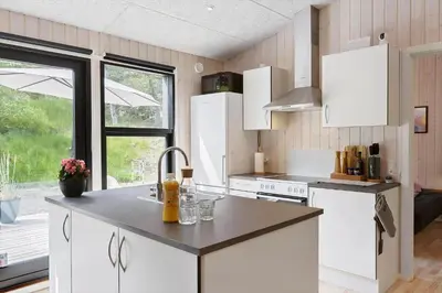 a kitchen with white cabinets and a large window at BL1565-Blokhus-Plantagevej-2-A in Blokhus
