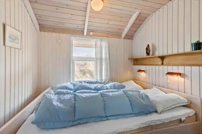 a large bed in a room with a window at BL1747-Blokhus-Norresundbyvej-22 in Blokhus