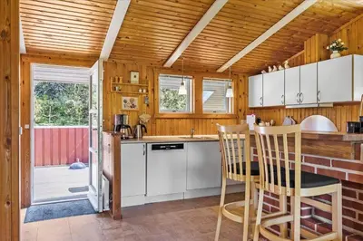 a kitchen with white cabinets and a table with chairs at BL410-Saltum-Store-Fiskerbanke-4 in Saltum