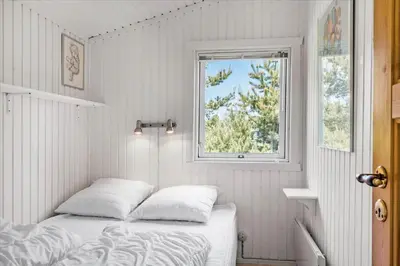 a white bedroom with a bed and a window at BL410-Saltum-Store-Fiskerbanke-4 in Saltum