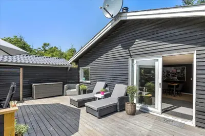 a patio with a couch and chairs on a deck at BL1417-Blokhus-Frederiksensvej-16 in Blokhus