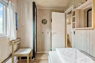 a bedroom with wooden walls and a bed and a chair at BL1522-Saltum-Kordalslien-25 in Saltum