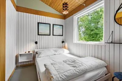 a bedroom with a bed in a room with a window at BL1728-Blokhus-Kaeruldvej-7 in Blokhus