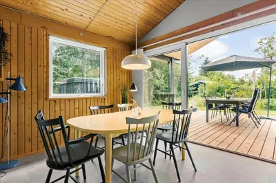 a dining room with a table and chairs on a deck at BL1728-Blokhus-Kaeruldvej-7 in Blokhus