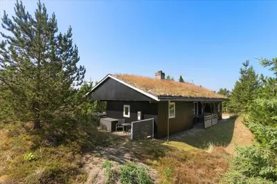 a small house with a grass roof on a hill at BL1136-Blokhus-Graevlingevej-6 in Blokhus