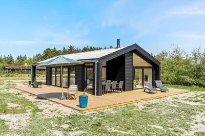 a house with a deck with chairs and an umbrella at BL1464-Saltum-Nordvestvej-34 in Saltum