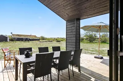 a wooden table with chairs and an umbrella on a deck at BL1464-Saltum-Nordvestvej-34 in Saltum