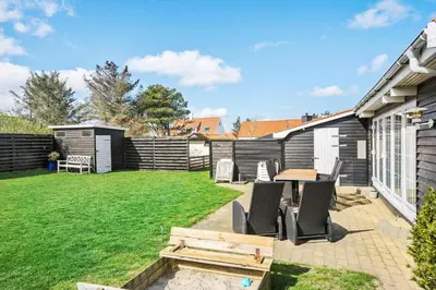 a patio with a table and chairs in a yard at BL856-Blokhus-Soren-Tjenersvej-2 in Blokhus