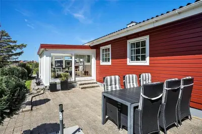 a patio with a table and chairs in front of a house at BL141-Blokhus-Vigen-12 in Blokhus