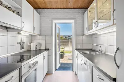 a kitchen with white cabinets and a door to a yard at BL141-Blokhus-Vigen-12 in Blokhus